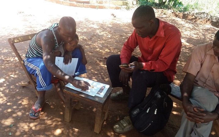 An enumerator interviews a pig farmer in Uganda