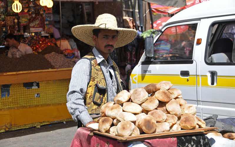 Man with bread piled on cart in street